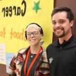 B.F. 一天 Counselors smile at camera while standing in front of yellow Career Week poster.